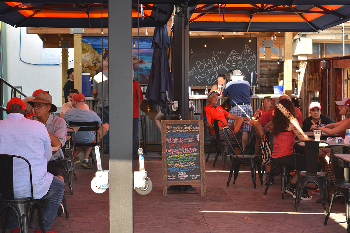 Broadway Oyster Bar Beer Garden photo with people enjoying drinks at tables with umbrellas and standing at bar